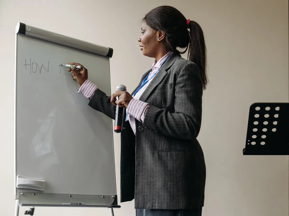 Eine Frau im Blazer schreibt bei einem Workshop etwas an ein Flipchart.