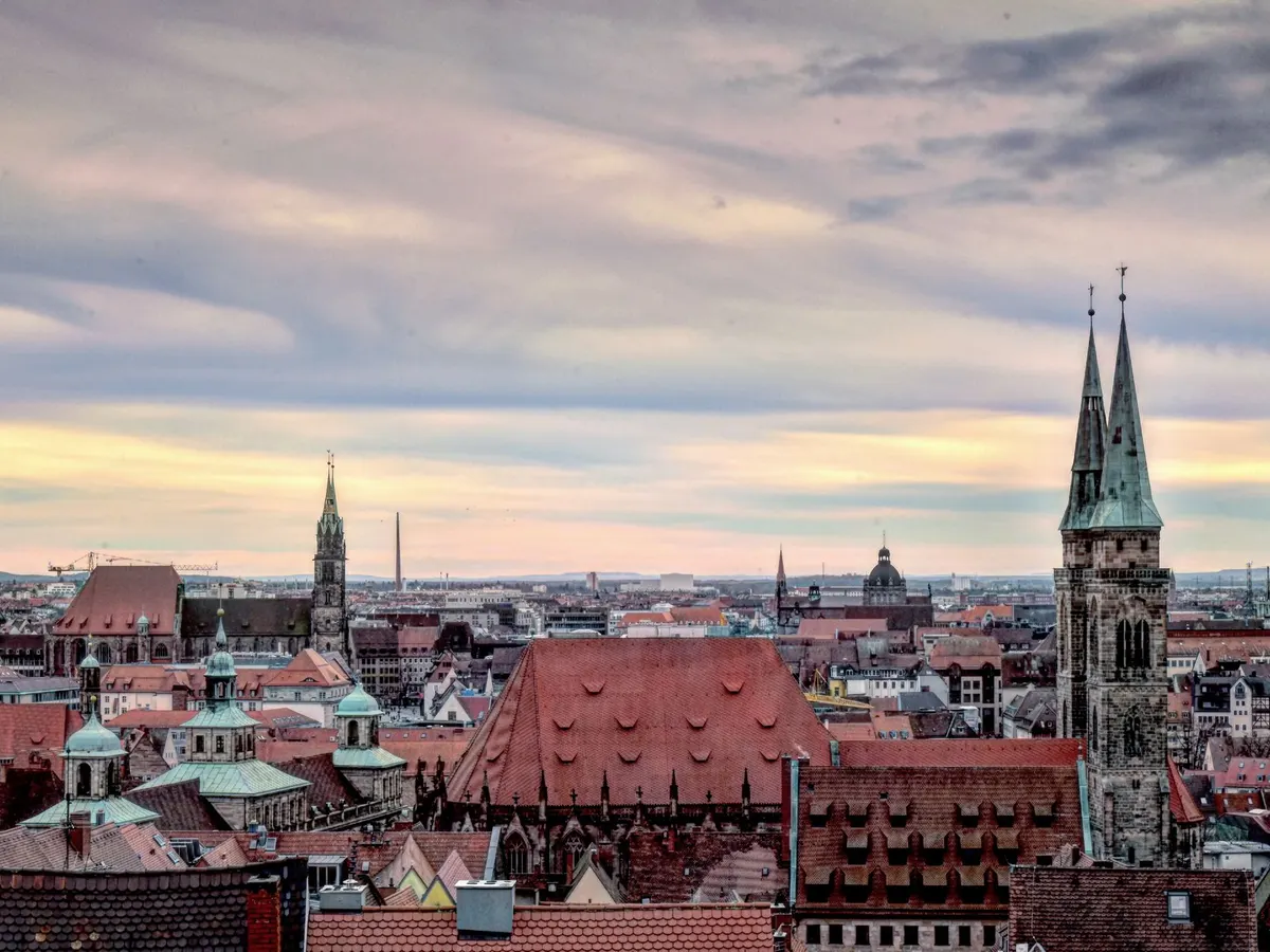 Blick über die Dächer der Nürnberger Altstadt mit den Türmen von St. Sebald unter einem weiten Abendhimmel.